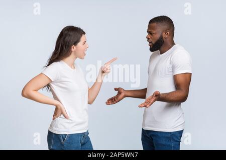 Interracial couple arguing, angry young woman blaming her afro boyfriend Stock Photo