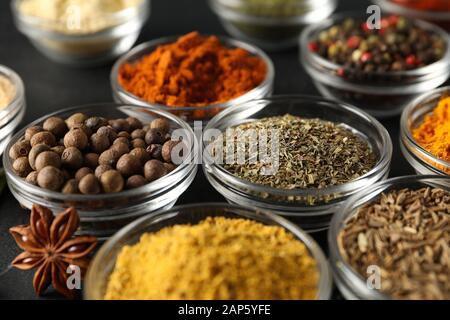 Bowls with different spices and ingredients on black background, close up Stock Photo