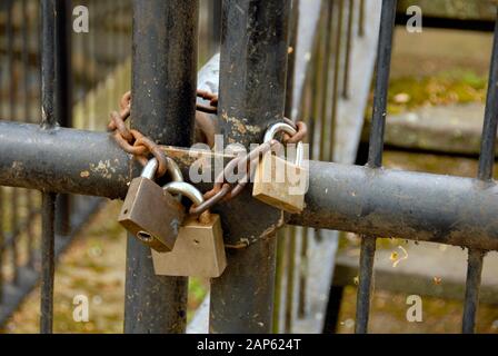 Three padlocks and a chain securing a gate Stock Photo