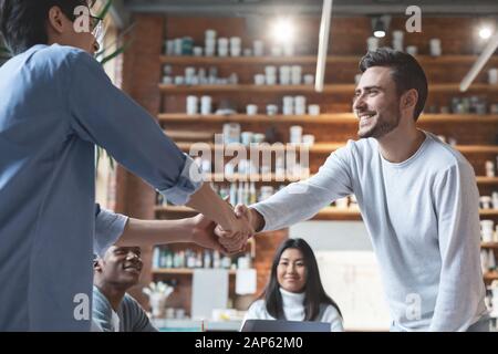 Close up of two guys colleagues shaking hands Stock Photo