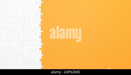 White jigsaw puzzle pieces on orange background copy space for your text. Business concept. Stock Photo