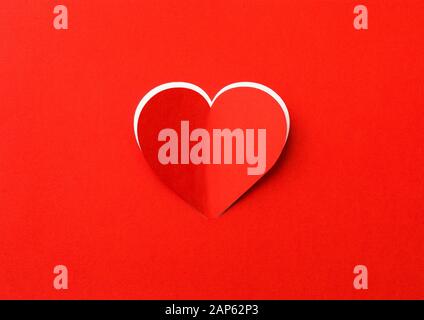 Valentines Day background. A red sheet of paper with a cut out heart. White background. Stock Photo