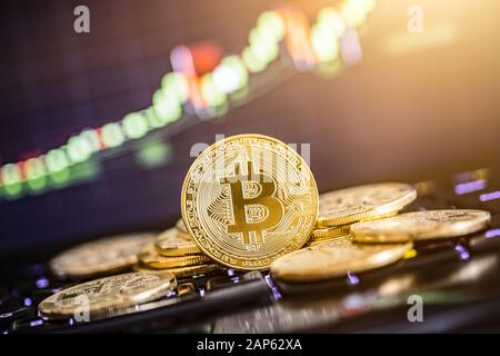 Bitcoin gold coin and defocused chart background. Virtual cryptocurrency concept. Stock Photo