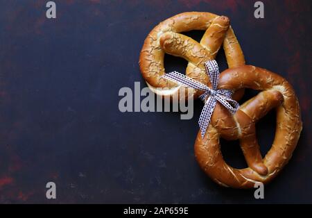 Concept of bavarian food. Traditional baked bavarian salted pretzels on dark background. Stock Photo