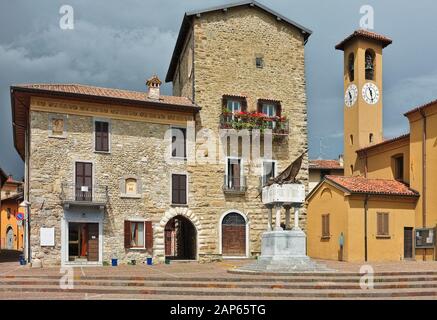 Garibaldi square with ancient watchtower, memorial war, church, bell tower and clock in Imbersago (LC), Brianza, Lombardy, Italy (2018) Stock Photo