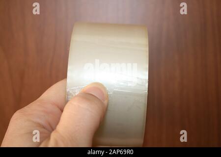 Wide adhesive tape in hand on wooden background Stock Photo