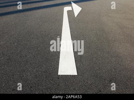 Close up of isolated white arrow on asphalt road showing right direction - Germany Stock Photo