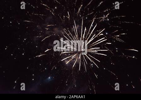 Bright yellow fireworks, with sparks and smoke, against the background of the night sky. Stock Photo