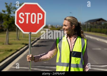 Woman wearing a high visibility vest and holding a stop sign Stock Photo