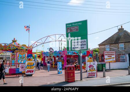 Dymchurch England - August 19 2019; Amusement Park entranceand road direction sign with people indulging in fun of the fair Stock Photo