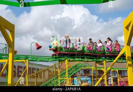 Dymchurch England - August 19 2019; Amusement Park  catapillar roller coaster being ridden by adults and children. Stock Photo