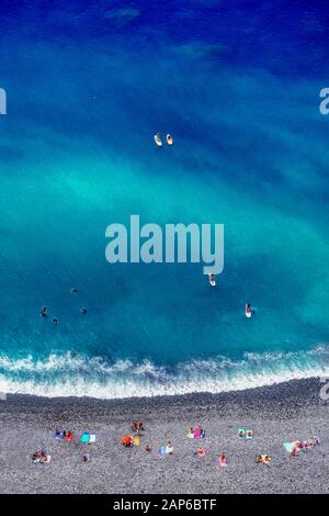 Tropical beach with colorful beach towls, people, divers and surfers - Top down aerial view Stock Photo
