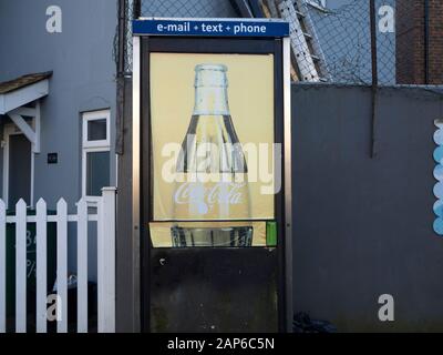 weather worn coca cola advertisement on BT phone box window Stock Photo