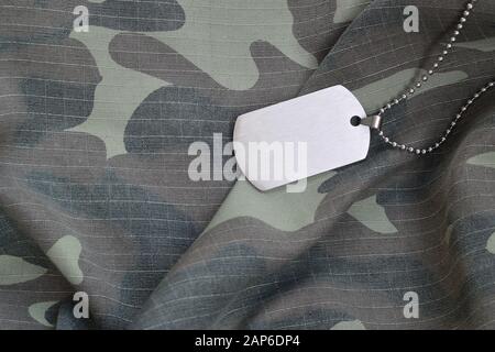Silvery military beads with dog tag on camouflage fatigue uniform. Army token on soldiers camo jacket rear part Stock Photo