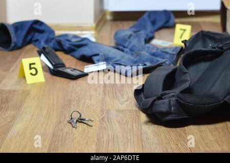 Crime scene investigation - numbering of evidences after the murder in the apartment. Keys, wallet and clothes with evidence markers close up Stock Photo