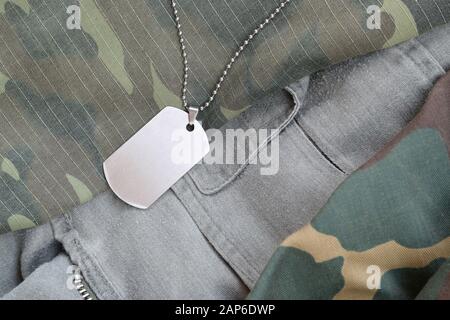 Silvery military beads with dog tag on different camouflage fatigue uniforms. Army token on soldiers camo jackets Stock Photo