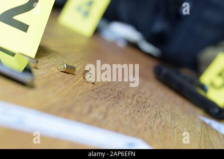 Id tents at crime scene after gunfight indoors. Gun cartridges as evidence on crime scene investigation process close up Stock Photo