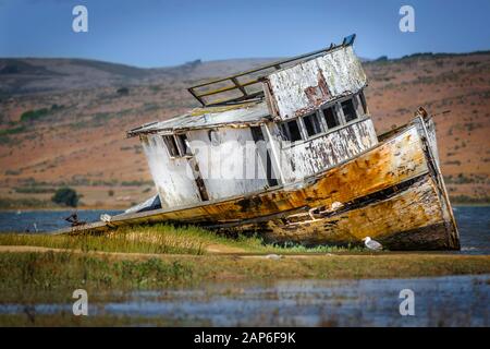 Old wooden fishing boat run aground on a sandbank near Inverness, California Stock Photo