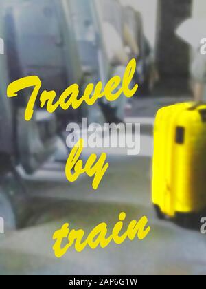 The inscription TRAVEL BY TRAIN on the background of the interior of the train car with a yellow suitcase Stock Photo