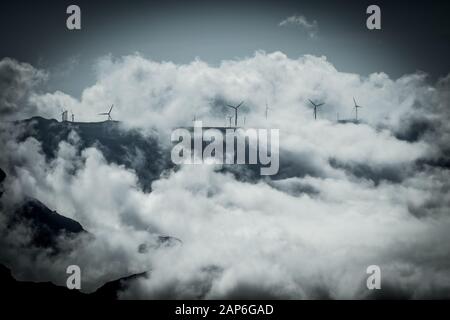 Wind power station installed on the mountain top with dramatic clouds Stock Photo