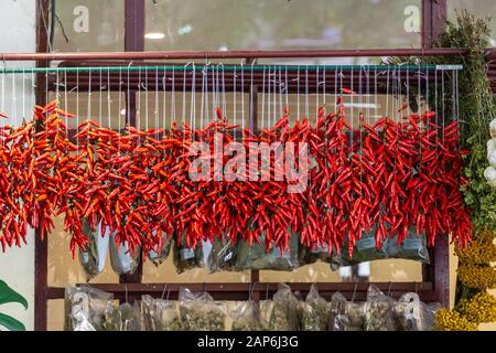 Red chili pepper chain hanging to dry in a market place Stock Photo
