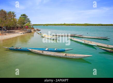 Wooden canoe on sea lagoon in Senegal in Africa. It is the Saloum National Nature Park, a bird sanctuary. In the background is blue sky and the island Stock Photo