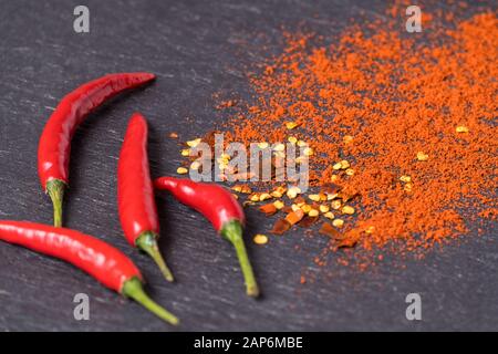 Flat lay red hot Chili peppers, red pepper flakes and chilli powder on black background. Stock Photo