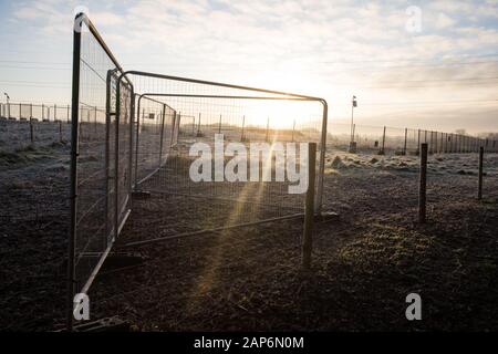 Harefield, UK. 21 January, 2020. The sun rises behind Heras fencing and security cameras on land in the Colne Valley designated for the HS2 high-speed rail link. Credit: Mark Kerrison/Alamy Live News Stock Photo