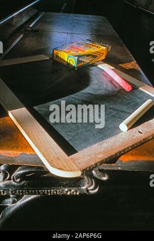 Vintage chalkboard with chalk sticks  on top of an school desk Stock Photo