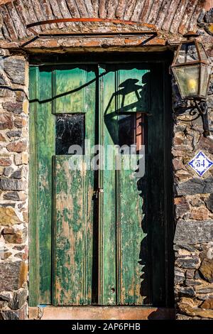 Old Spanish style green door with stone wall and lantern Stock Photo