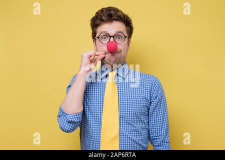 My mouth is fortress,will not tell anybody. Funny caucasian man in glasses and clown nose making gesture with hand, zipping lips, promising to keep se Stock Photo