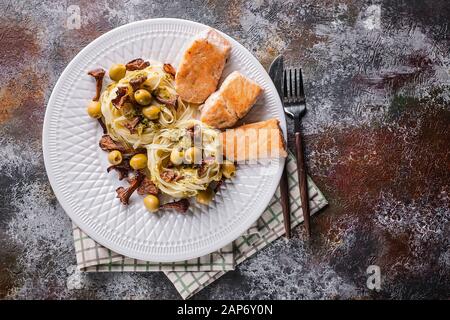 Top view fried salmon, tagliatelle with pesto sauce, fried chanterelles and olives. Seafood and Italian Pasta. Copy space Stock Photo
