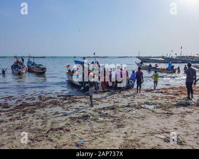 MBour, Senegal- April 25 2019: Unidentified Senegalese men and women waiting for the fishermen at the fish market in the port city near Dakar. There Stock Photo