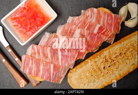 Toast of bread with acorn-fed Iberian ham on stone slate Stock Photo