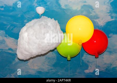 Fragment of a ceiling stylized as a vault of heaven with lamps in the form of clouds and balloons close-up. Stock Photo