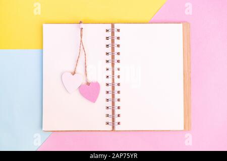 Open otebook with pink and white wooden hearts on them. Send message to your lover on Valentine's day. Stock Photo