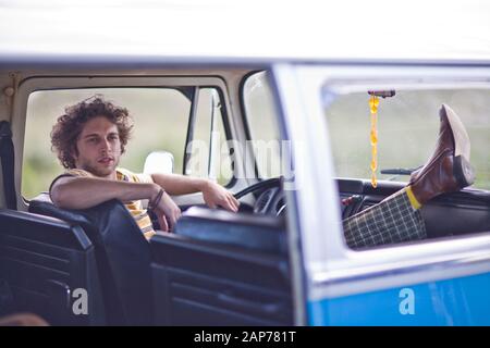 Young man sitting with his feet up inside a van. Stock Photo
