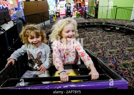 two girls smiling and laughing on rollercoaster having fun Stock Photo