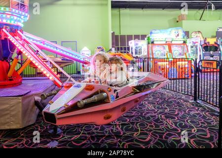 two girls on indoor amusement park ride having fun Stock Photo