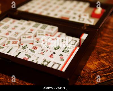 A set of Mahjong tiles in a black wooden box. Mahjong is a tile-based game that was developed in China during the Qing dynasty. Stock Photo