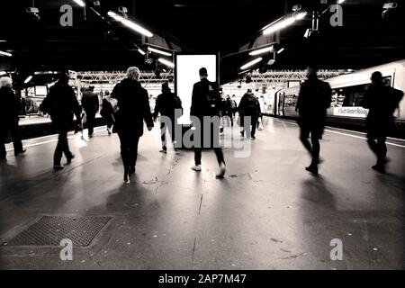 Passengers at Waterloo train station London entering the platform to board a South Western Railway train going home at the end of working day commute Stock Photo
