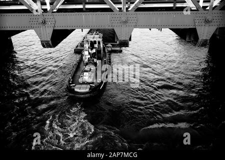 Tideway Class barge laden full with spoil from Thames Tideway Tunnel infrastructure project being pushed down the River Thames in London by Tug boat Stock Photo