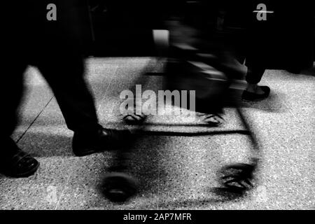 Commuters rushing to and from work on London Underground their legs and feet showing motion blur of a slow exposure in monochrome black and white Stock Photo