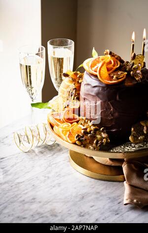 An Epic Gluten-free Chocolate Cake with ricotta cheese filling, chocolate frosting, chocolate glaze, orange slices and pistachio praline served with c Stock Photo