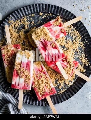 Strawberry rhubarb pie à la mode popsicles have strawberry rhubarb compote layered up with luscious vanilla bean cream and crumbles of pie crust on to Stock Photo