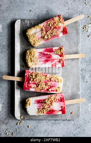 Strawberry rhubarb pie à la mode popsicles have strawberry rhubarb compote layered up with luscious vanilla bean cream and crumbles of pie crust on to Stock Photo