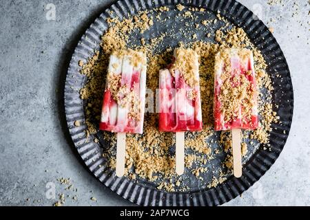 Strawberry rhubarb pie à la mode popsicles have strawberry rhubarb compote layered up with luscious vanilla bean cream and crumbles of pie crust on to Stock Photo