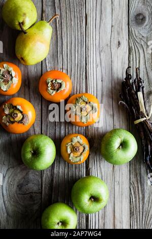 Persimmon and apples on a wooden background Stock Photo