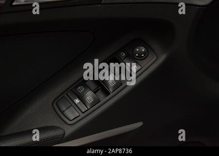 The control buttons for opening and closing windows of doors and electric controls and settings of mirrors on the door in black with leather upholster Stock Photo