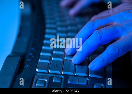 A man works at a computer. Hands of a man on the keyboard close-up. Programmer or hacker. Side view Stock Photo